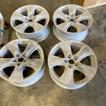 Four bare machined alloy wheels ready for refinishing