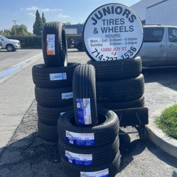Junior's Tires & Wheels sign with stacks of new tires
